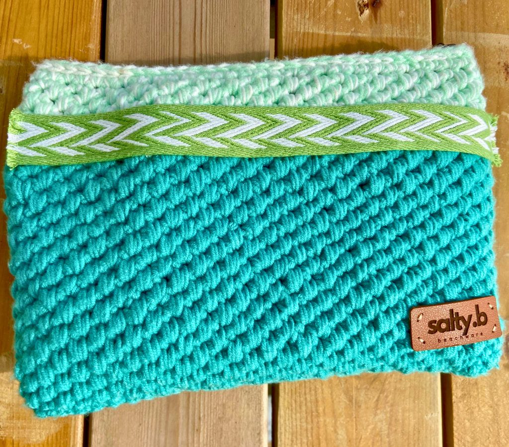 Turquoise crochet zipper pouch on a wood deck.